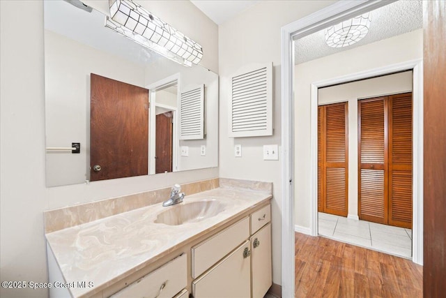 bathroom with a textured ceiling, vanity, and hardwood / wood-style flooring