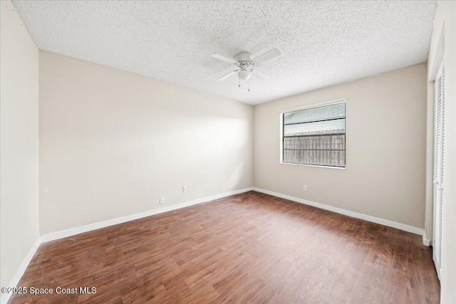 empty room with a textured ceiling, ceiling fan, and dark wood-type flooring