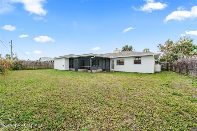 rear view of property featuring a yard and a sunroom