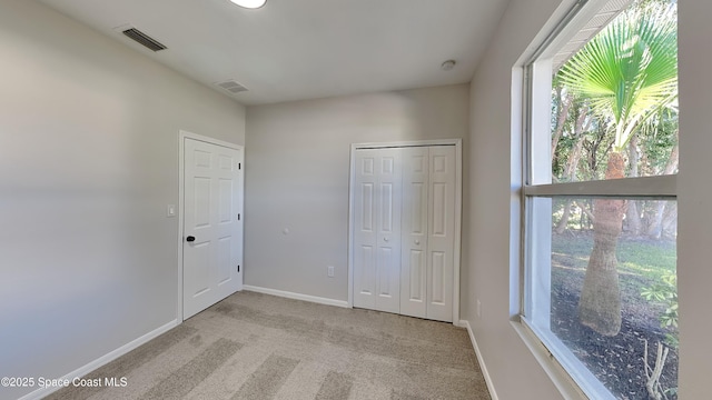 unfurnished bedroom with a closet, light colored carpet, and multiple windows