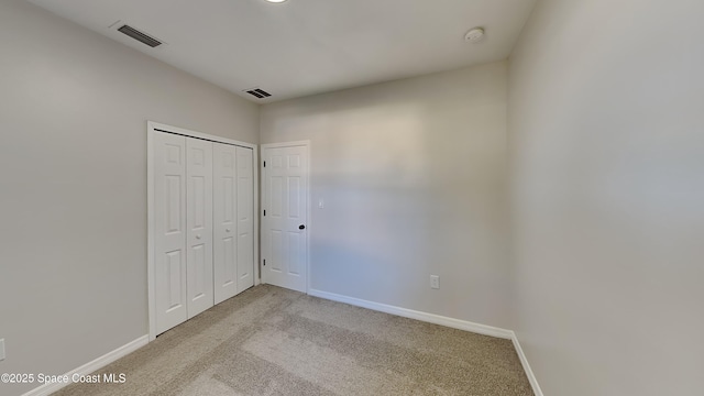 unfurnished bedroom with light colored carpet and a closet