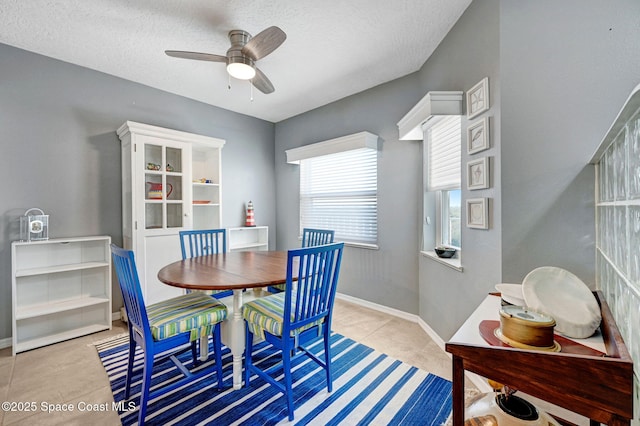 dining room featuring ceiling fan, a textured ceiling, baseboards, and light tile patterned floors