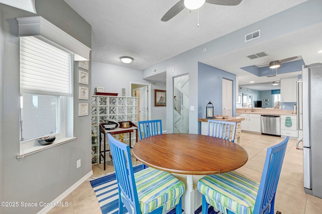 dining area with a textured ceiling, light tile patterned flooring, and visible vents