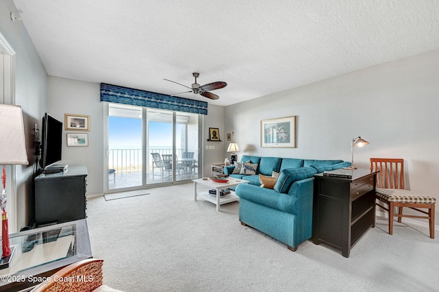 living area featuring carpet floors, a textured ceiling, and a ceiling fan