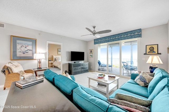 carpeted living area with visible vents, ceiling fan, a textured ceiling, and baseboards