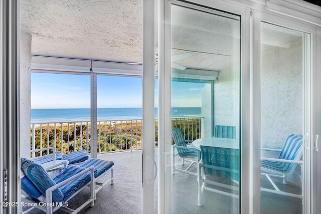 doorway to outside with a water view, expansive windows, and a view of the beach