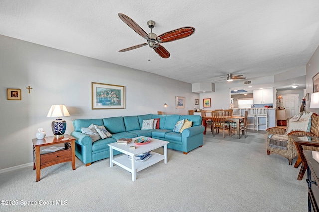 living area featuring light carpet, visible vents, a ceiling fan, and a textured ceiling