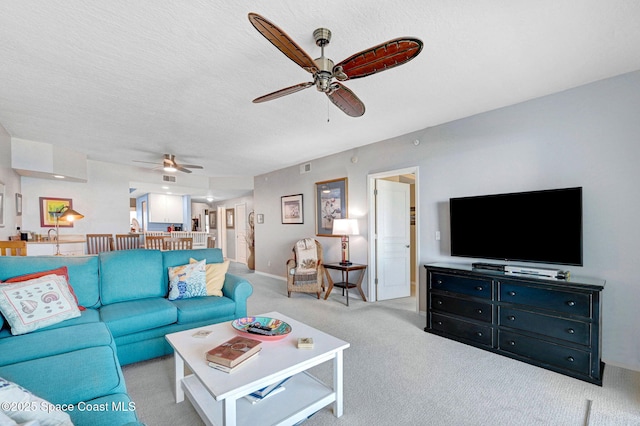 carpeted living room featuring ceiling fan and a textured ceiling