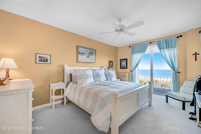 bedroom with light carpet, baseboards, ceiling fan, a water view, and access to exterior