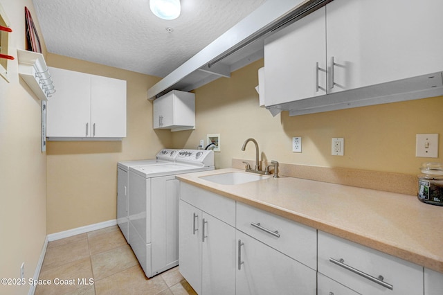 laundry area featuring light tile patterned floors, sink, cabinets, independent washer and dryer, and a textured ceiling