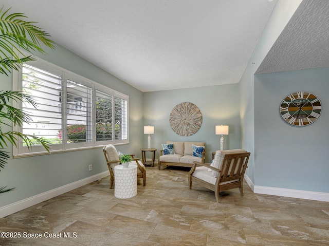 living area featuring a textured ceiling and baseboards