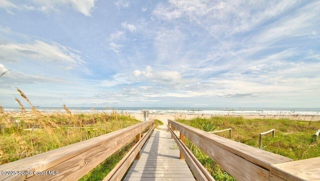 view of property's community featuring a water view and a beach view