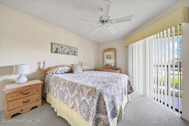 bedroom featuring a textured ceiling, light colored carpet, and ceiling fan