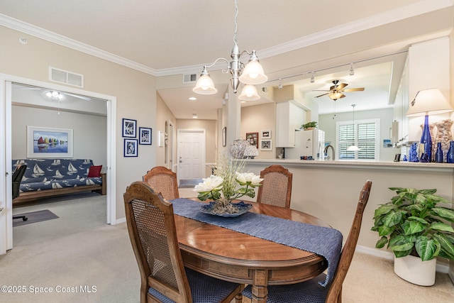 carpeted dining room featuring crown molding, sink, track lighting, and ceiling fan with notable chandelier