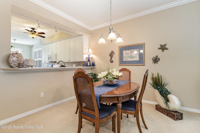 carpeted dining space with ceiling fan with notable chandelier, rail lighting, and ornamental molding