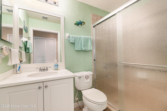 bathroom featuring a textured ceiling, vanity, toilet, and walk in shower