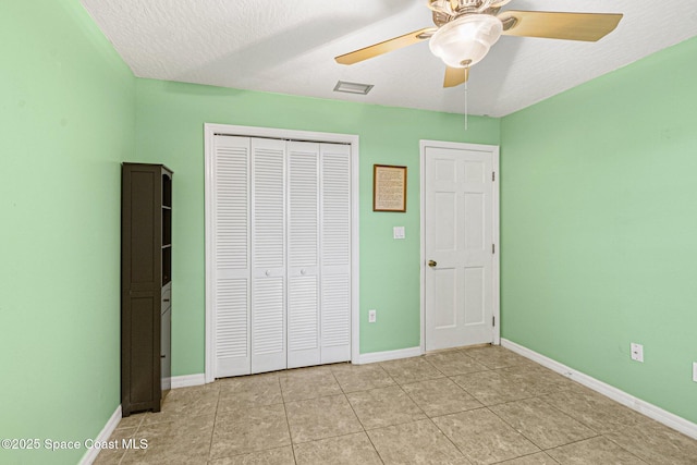 unfurnished bedroom with a textured ceiling, ceiling fan, and a closet