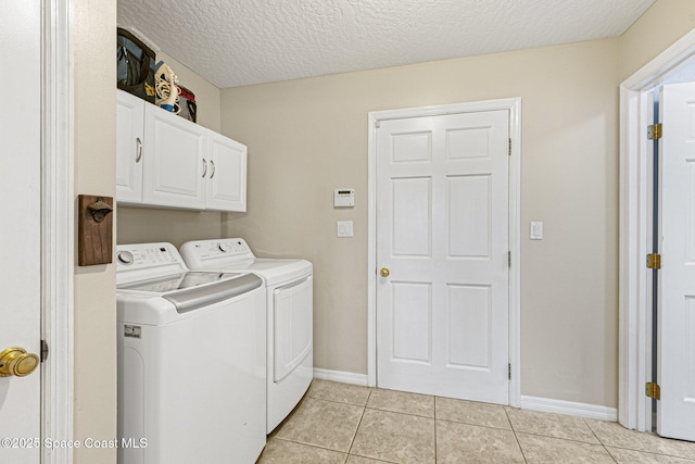 laundry room with cabinets, light tile patterned flooring, separate washer and dryer, and a textured ceiling