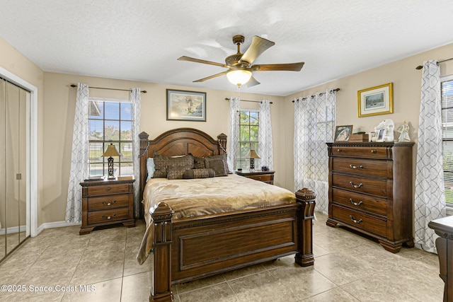 bedroom with a textured ceiling, a closet, ceiling fan, and light tile patterned flooring