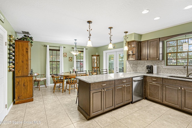 kitchen with sink, hanging light fixtures, light stone counters, french doors, and kitchen peninsula