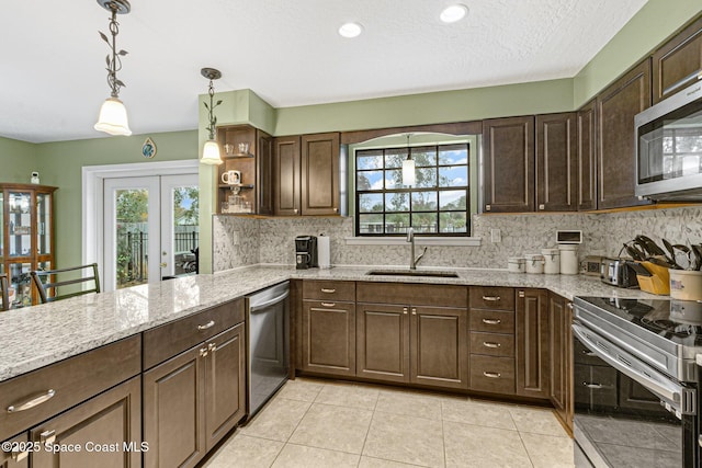 kitchen featuring pendant lighting, sink, stainless steel appliances, light stone counters, and french doors