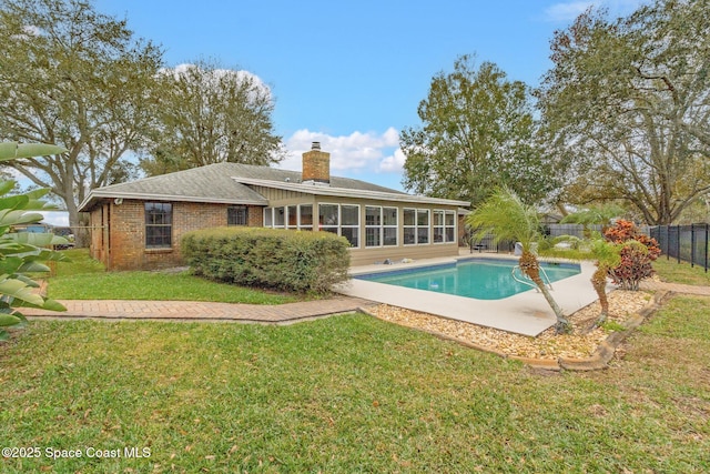 rear view of house featuring a fenced in pool, a yard, and a sunroom