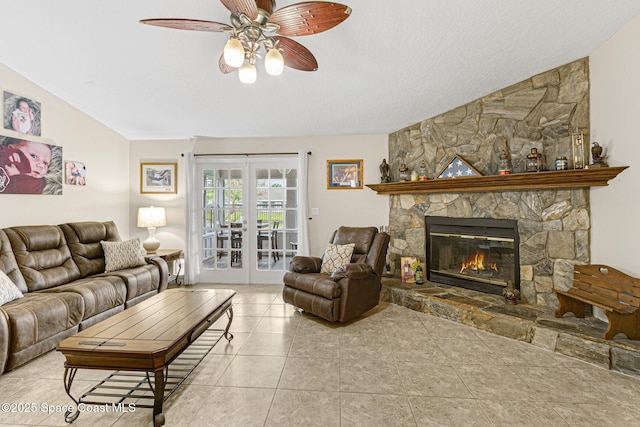 living room with french doors, ceiling fan, a stone fireplace, and light tile patterned floors