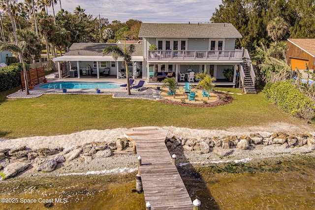 rear view of property featuring a patio area, a lawn, and a water view