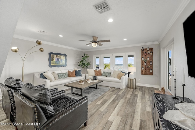 living room with ceiling fan, a textured ceiling, ornamental molding, and light hardwood / wood-style floors