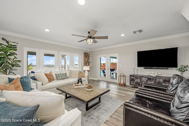 living room with ceiling fan, crown molding, french doors, and light wood-type flooring