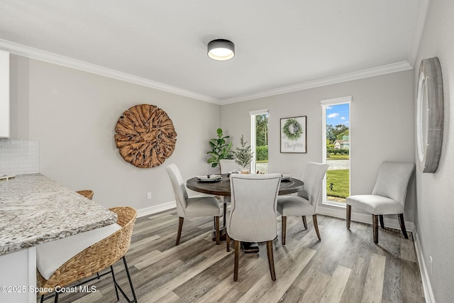 dining area featuring light wood-type flooring and crown molding