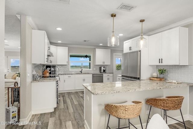 kitchen with pendant lighting, white cabinets, kitchen peninsula, and stainless steel appliances