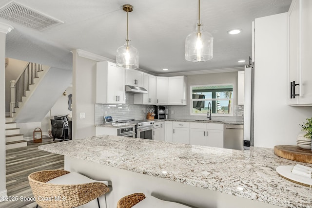 kitchen with kitchen peninsula, sink, stainless steel appliances, and white cabinetry