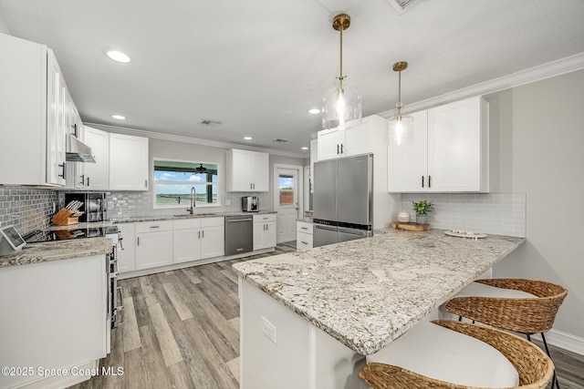 kitchen with pendant lighting, white cabinets, stainless steel appliances, sink, and kitchen peninsula