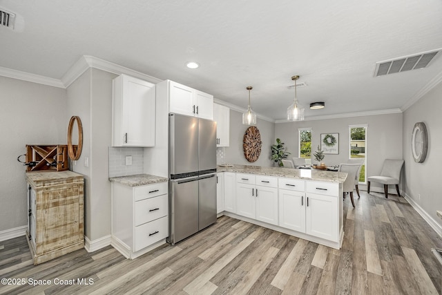 kitchen with pendant lighting, white cabinetry, stainless steel fridge, and kitchen peninsula