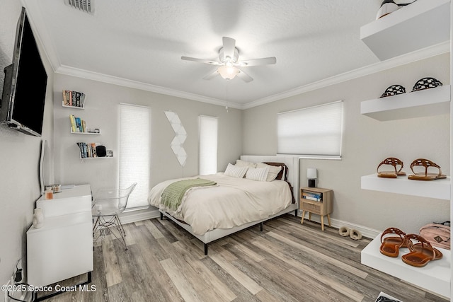 bedroom featuring ceiling fan, light hardwood / wood-style floors, a textured ceiling, and ornamental molding