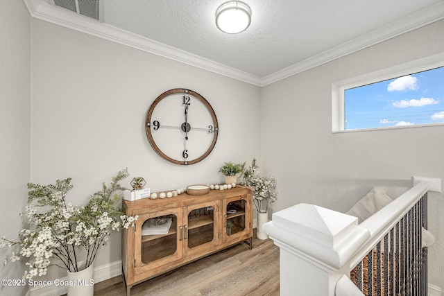 bathroom featuring hardwood / wood-style floors, ornamental molding, and a textured ceiling