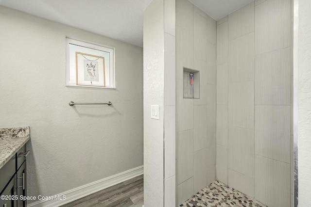 bathroom featuring vanity, tiled shower, and hardwood / wood-style flooring