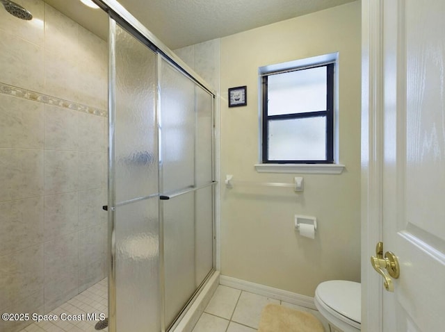 bathroom featuring tile patterned flooring, toilet, and a shower with shower door