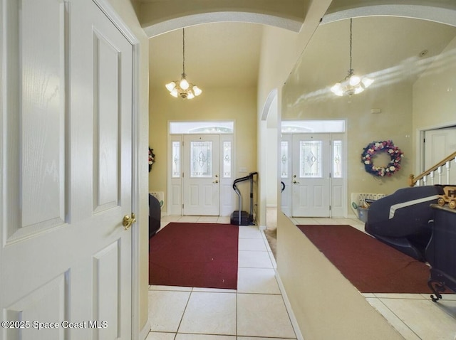 tiled entryway with a chandelier and a towering ceiling