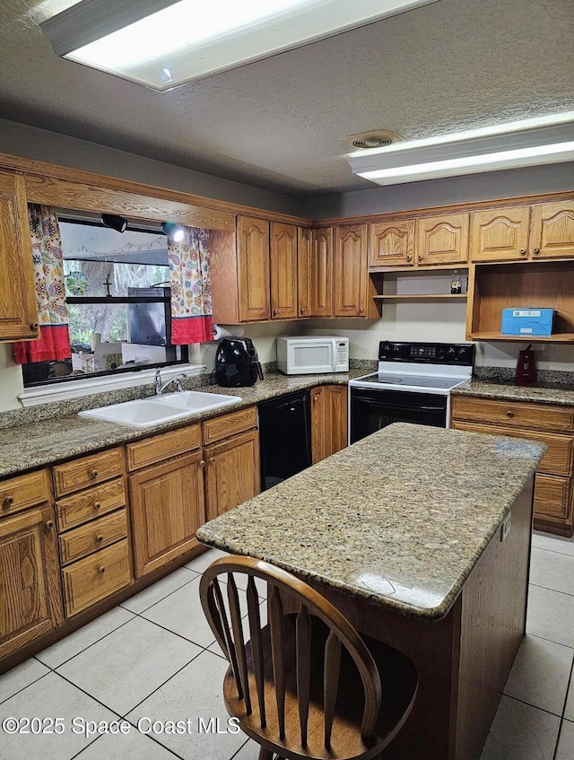 kitchen featuring light stone counters, white appliances, sink, a center island, and light tile patterned flooring