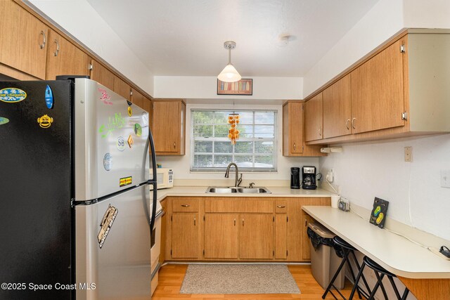 405 Adams Ave Unit 10, Cape Canaveral, FL 32920 - kitchen featuring freestanding refrigerator, light wood-style flooring, white microwave, light countertops, and pendant lighting