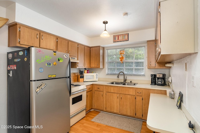 405 Adams Ave Unit 10, Cape Canaveral, FL 32920 - kitchen featuring white appliances, light countertops, light wood-type flooring, under cabinet range hood, and brown cabinetry