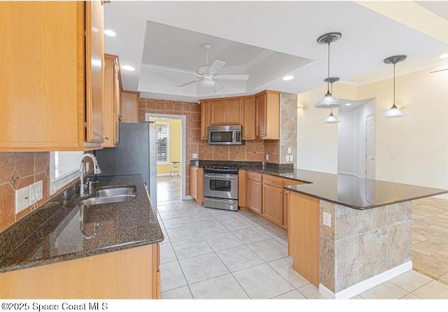 kitchen featuring pendant lighting, a raised ceiling, dark stone countertops, appliances with stainless steel finishes, and kitchen peninsula