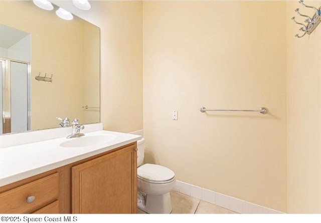 bathroom featuring tile patterned flooring, vanity, toilet, and a shower with door