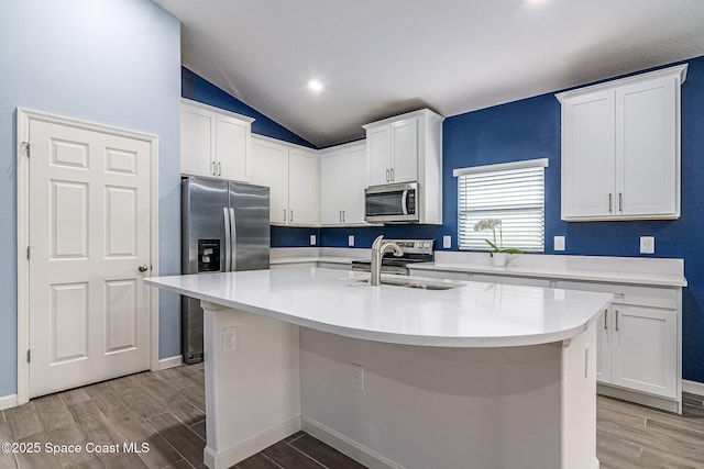 kitchen with appliances with stainless steel finishes, sink, a center island with sink, and white cabinets