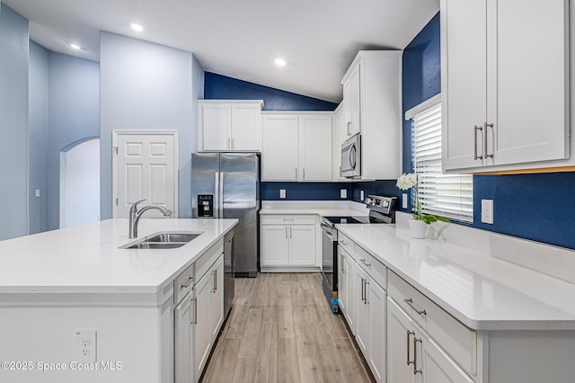 kitchen with vaulted ceiling, white cabinetry, sink, a kitchen island with sink, and stainless steel appliances