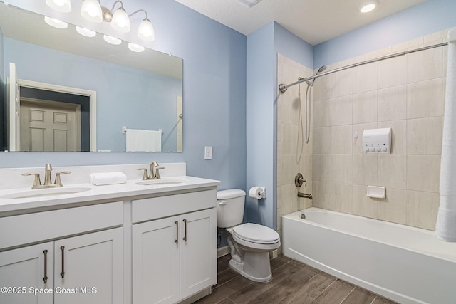 full bathroom featuring hardwood / wood-style flooring, tiled shower / bath, vanity, and toilet