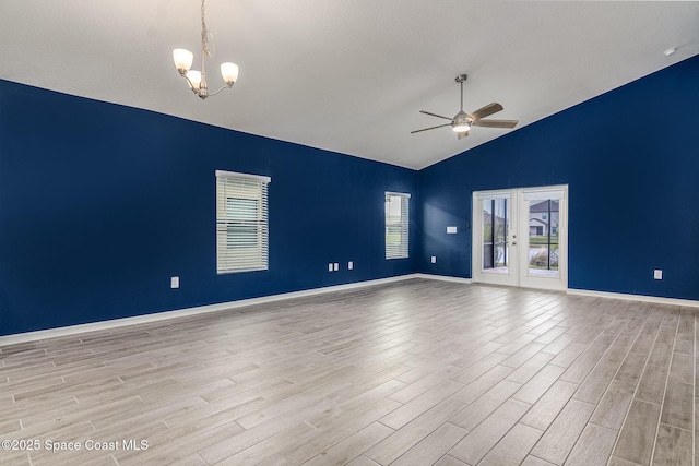 empty room featuring french doors, high vaulted ceiling, ceiling fan with notable chandelier, and light hardwood / wood-style flooring