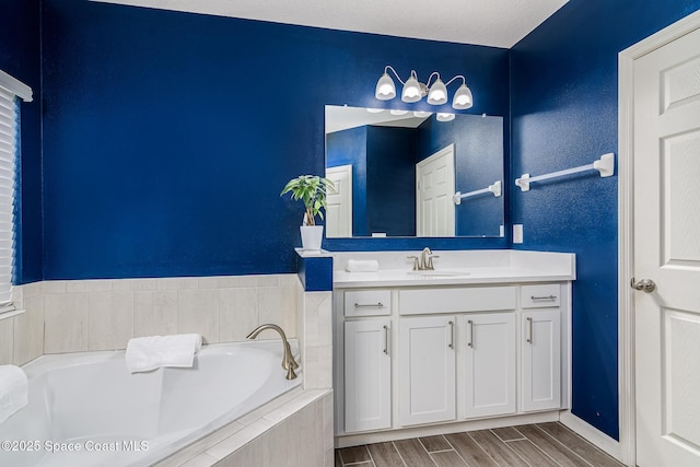 bathroom featuring vanity and tiled bath